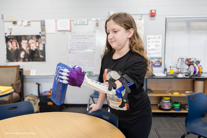 Student picking up object with arm