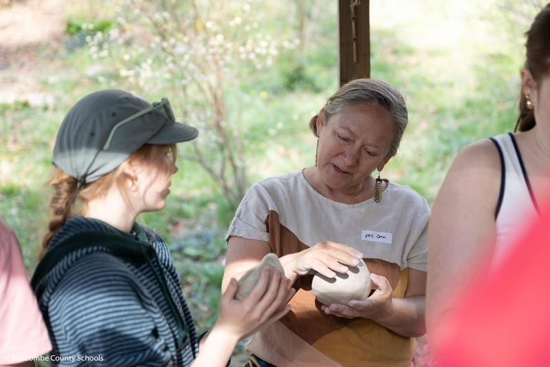 The owner of Firefly Valley Pottery talking to a student as they shape their clay.