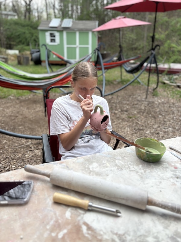 Student painting her piece of pottery.