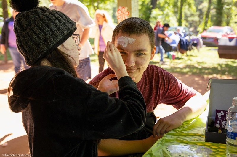 A student paints the face of another student.