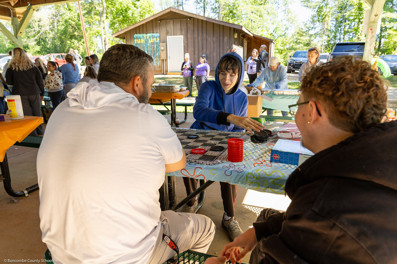 A student and adult play checkers.