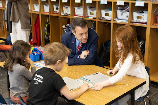Dr. Jackson seated at a table with 3 elementary students.