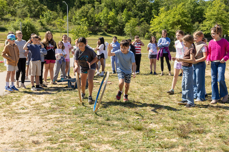 Two students race hoops on the lawn.