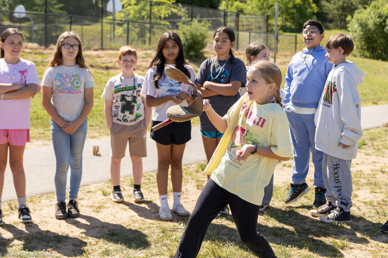 A girl catches a weighted bag with a stick.