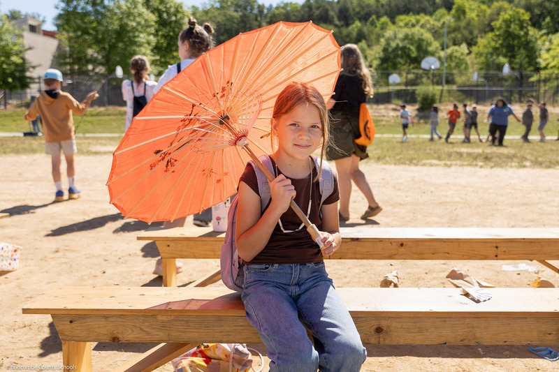 A student poses under a parasol.