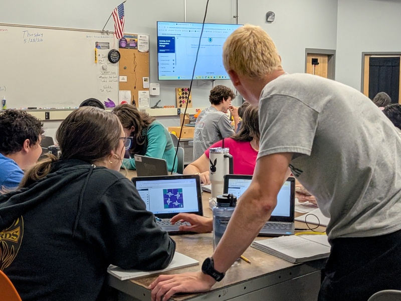 Students huddle around a laptop working on a group project in Engineering class.
