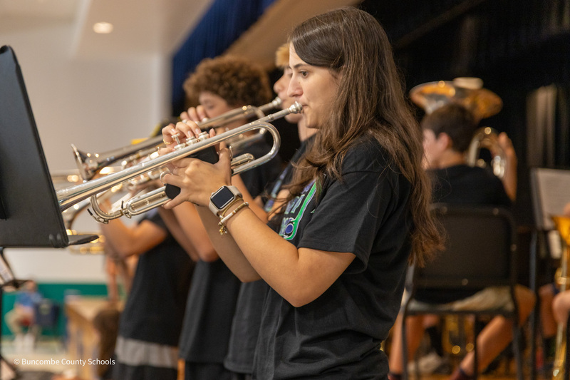 A student stands and plays the trumpet.