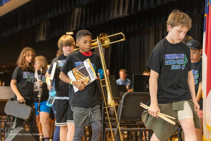 Students holding their instruments walk across the stage.