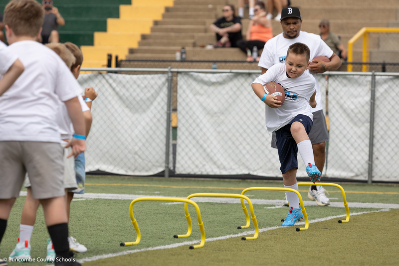 Kid running hurdles with a football in hand. 