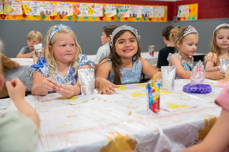 Girls in fairy tale costumes snack at a table.