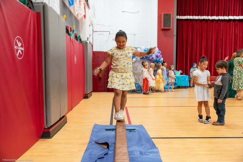 A girl walks on a balance beam.