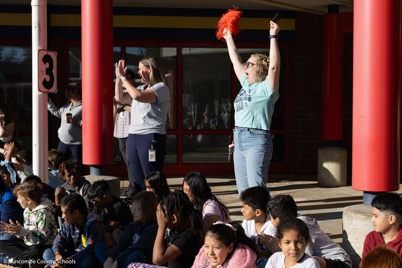 Teachers and students cheering for the friends as they arrive to school in the firetruck. 