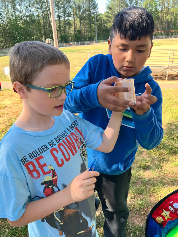 Students holding up a sample of dirt they collected. 