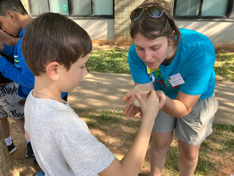 Student showing the Project Explore instructor their sample of dirt they collected. 