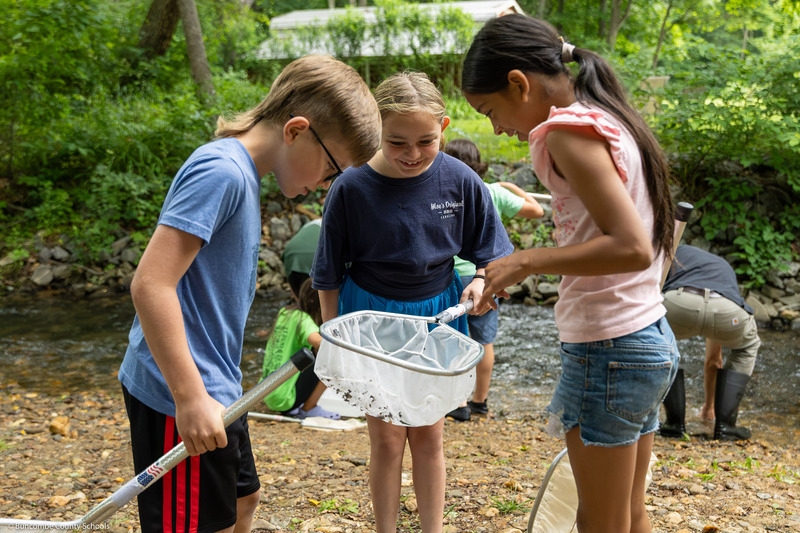 A boy and two girls look in a net.