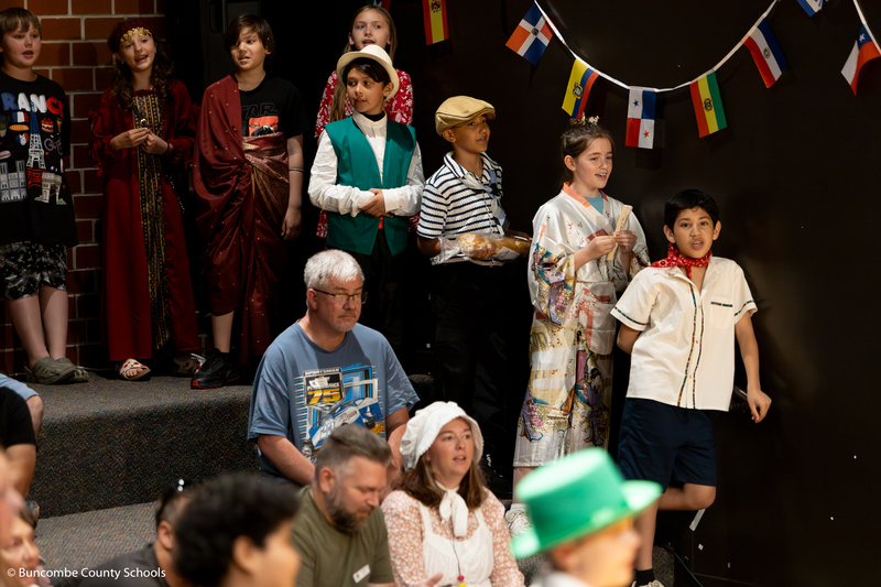 Students standing in the audience singing. 