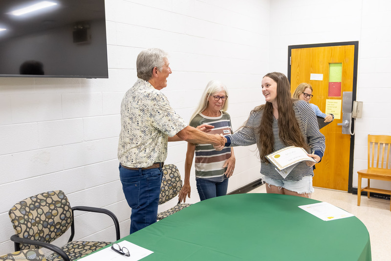 A recipient shakes hands with Mr. Johnson and receives her certificate.