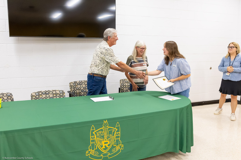 A recipient shakes hands with Mr. Johnson and receives her certificate.