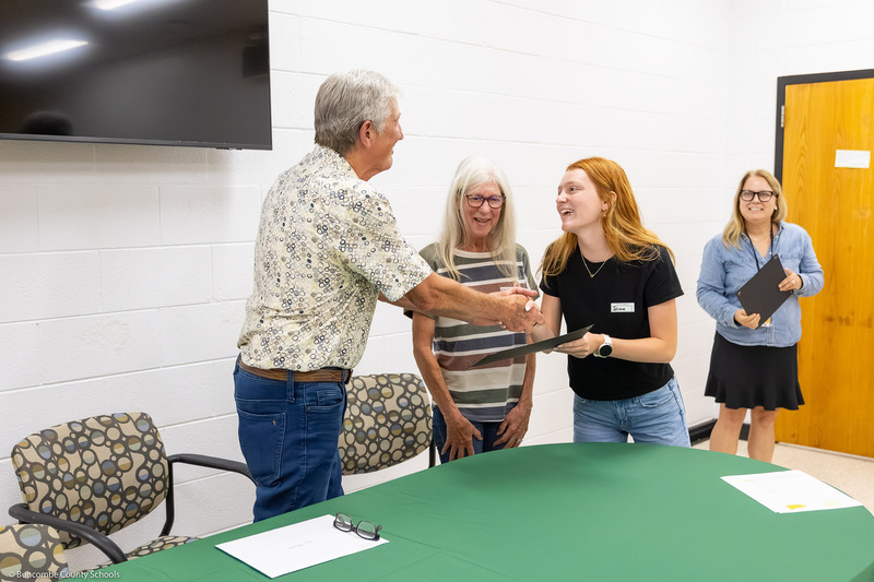 A recipient shakes hands with Mr. Johnson and receives her certificate.