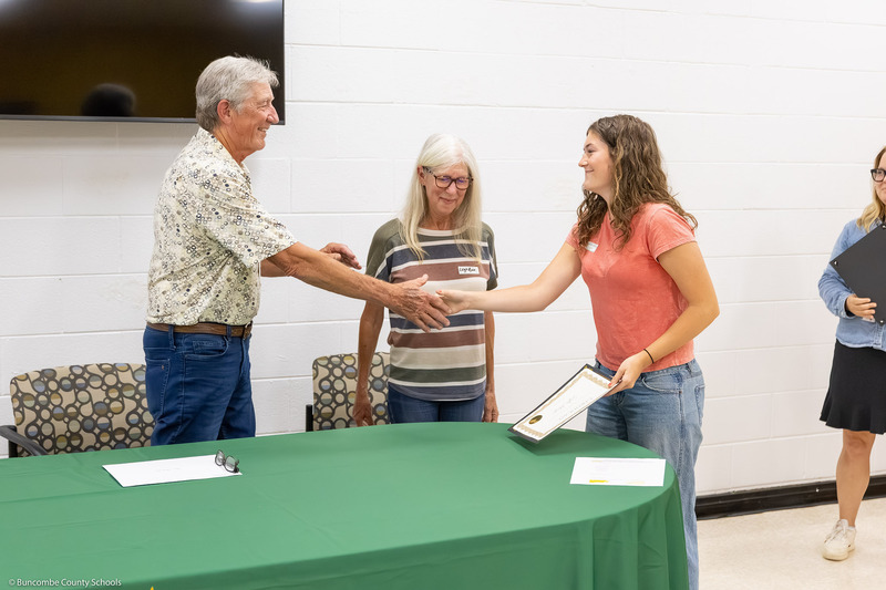 A recipient shakes hands with Mr. Johnson and receives her certificate.