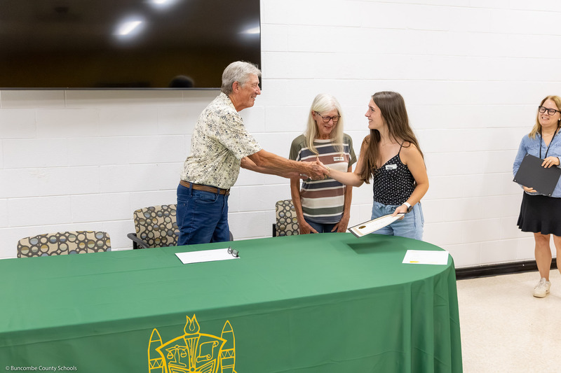 A recipient shakes hands with Mr. Johnson and receives her certificate.