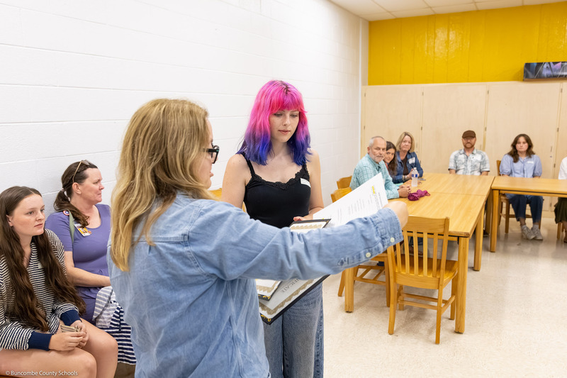 A recipient receives her certificate from Emily Walters.