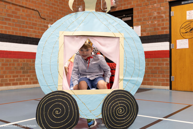 Boy dressed as a prince sitting in Cinderella's carriage. 