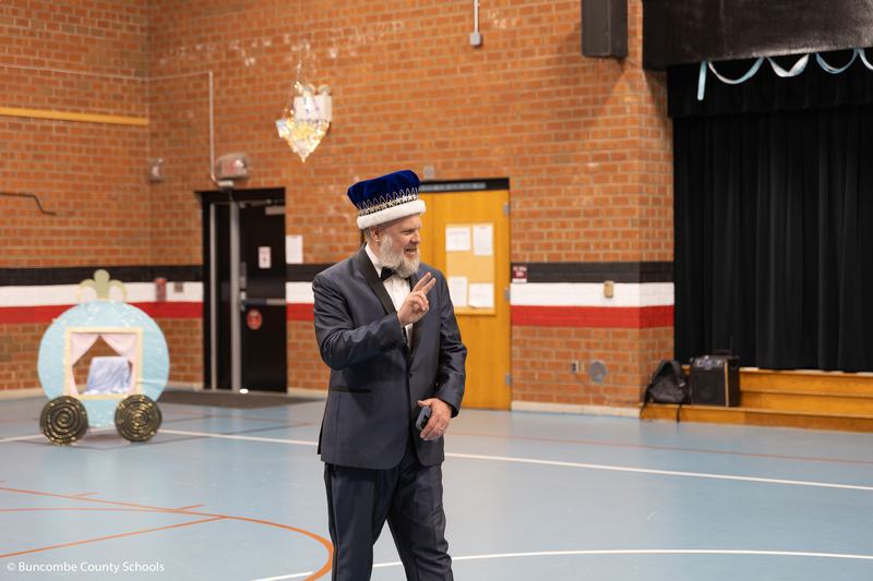 Teacher dressed in suite and wearing a crown. 