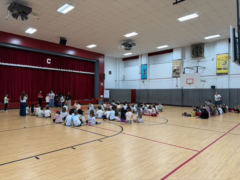Students sitting on the gym floor watching teammates compete with their multiplication facts. 