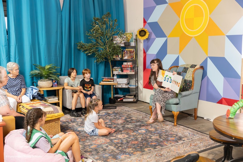 Teacher reading to community members and kids