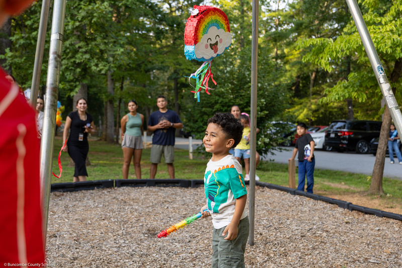 A boy smiles underneath a pinata.