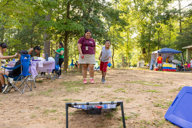 A boy and an adult play cornhole together.