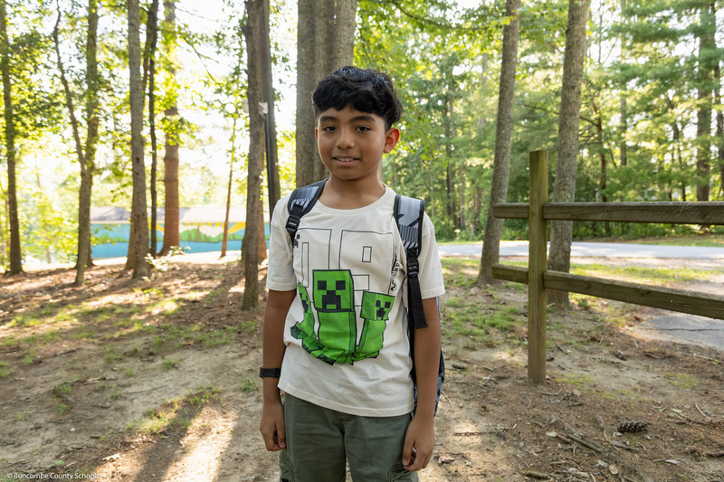 A boy poses while wearing a new backpack.