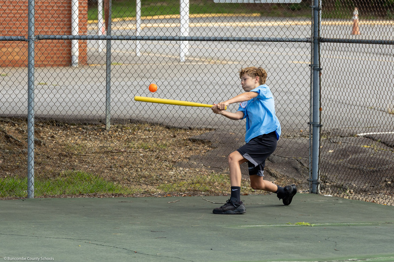 A boy hits a plastic ball with a plastic bat.