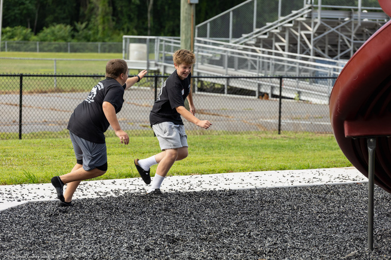 A boy chases another boy on the playground.