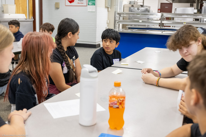 A sixth graders looks over his right shoulder while talking to a group.