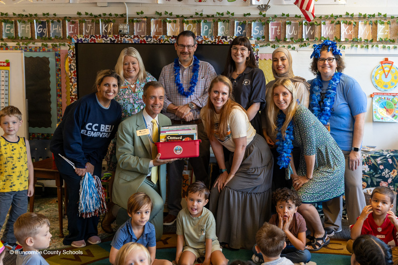 A group of Bell staffers surround Dr. Jackson holding the bin of books.