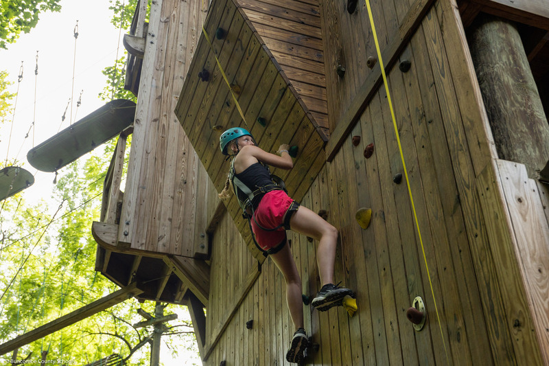 A girl climbs a rock wall.