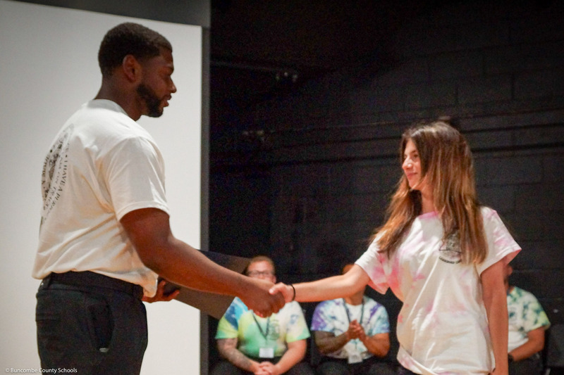 A girl in a tye-dye shirt shakes hands with an SRO.