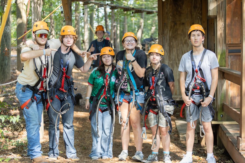 students stand and smile in helmets and harnesses