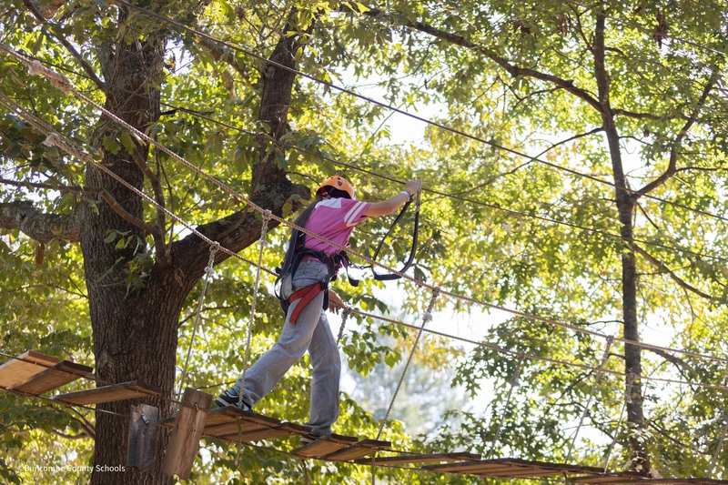 student crosses a rope bridge