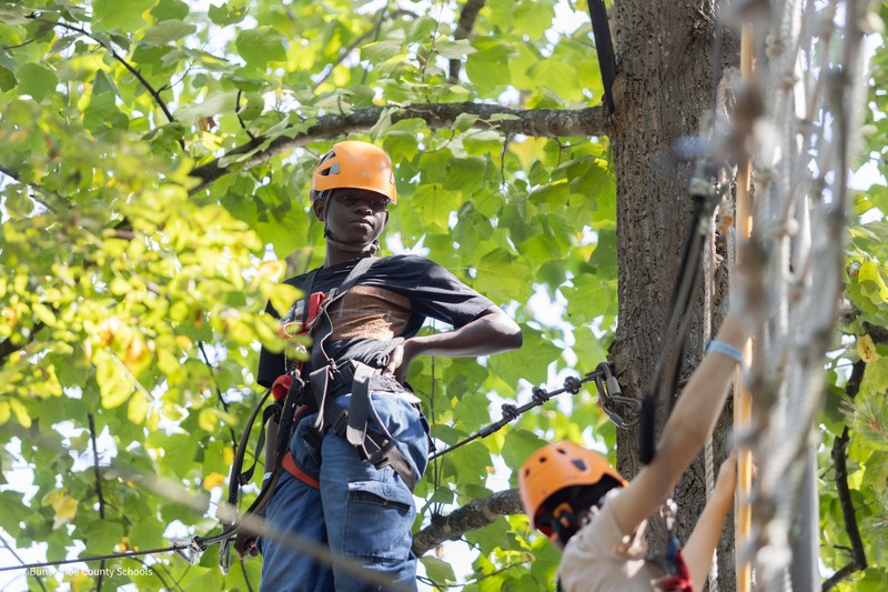 student stands on platform in tree