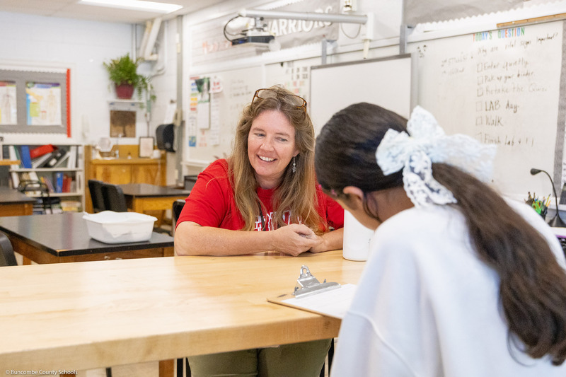 A teacher smiles while answering a question.