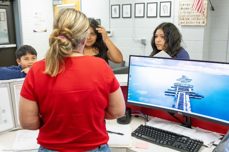 A staff member talks to students at the school's front desk.