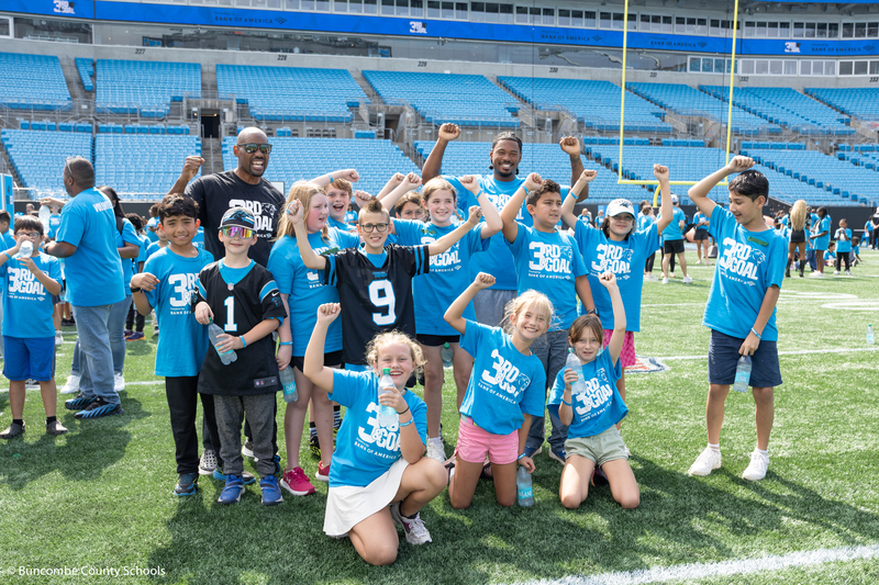 Group photo of kids with two former Panther players