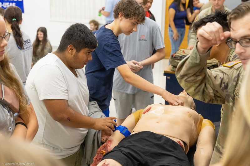 Students practice applying a tourniquet to the mannequin.