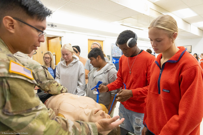 Students practice applying a tourniquet to the mannequin.