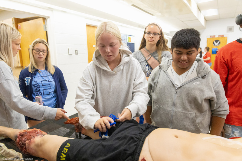 Students practice applying a tourniquet to the mannequin.