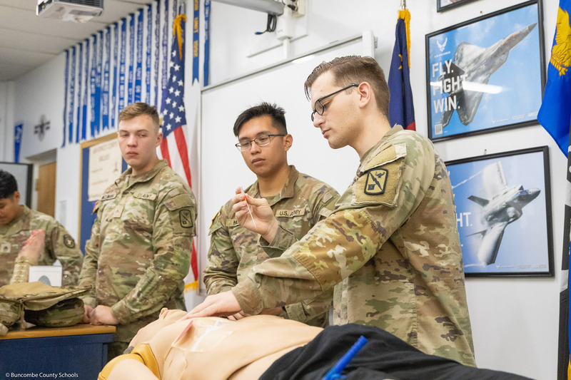 Members of the U.S. Army Traveling Medical Team speaks to students behind a mannequin.