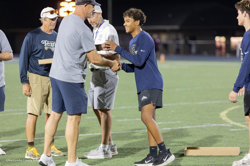 student shakes hand while receiving championship ring